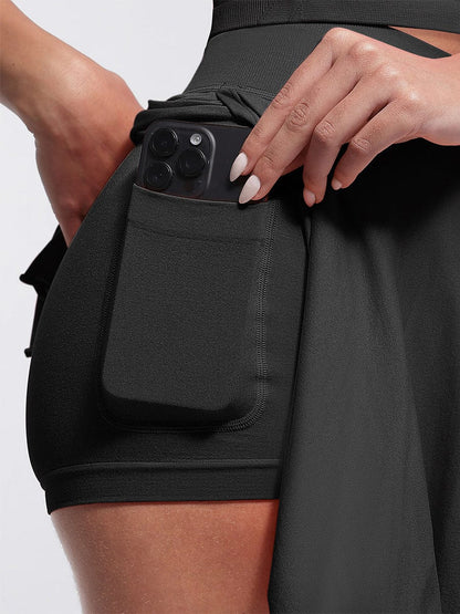 Falda acampanada con cintura media, corte A, bajo con volantes, pantalones cortos y bolsillos incorporados.